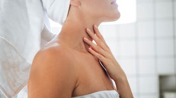 Mujer poniéndose crema en el cuello